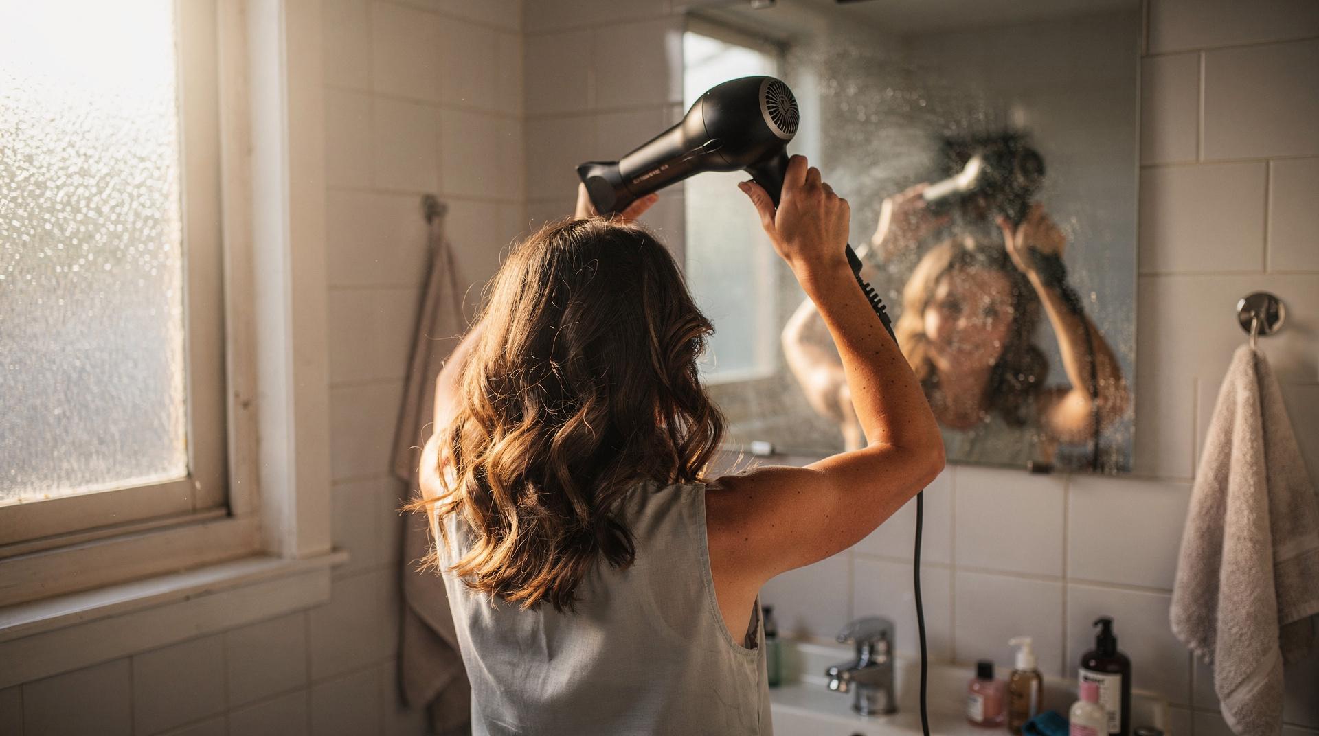 Femme aux cheveux wavy naturels se coiffant devant un miroir
