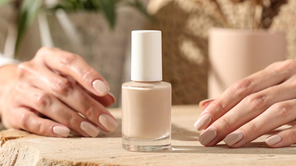 Flacon de vernis à ongles bio près de mains manucurées