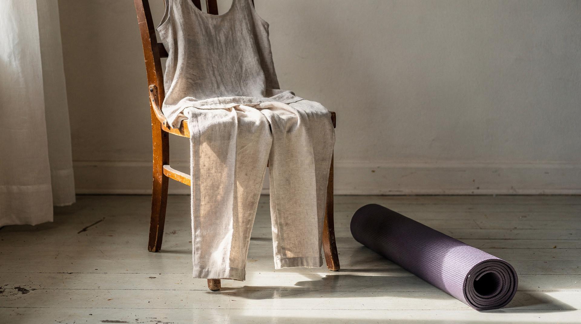 Tenue après-yoga en lin et coton posée près d'un tapis de yoga roulé, tons naturels